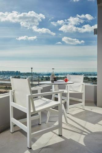 two white chairs and a table on a balcony at CW Athens Riviera Suite in Athens