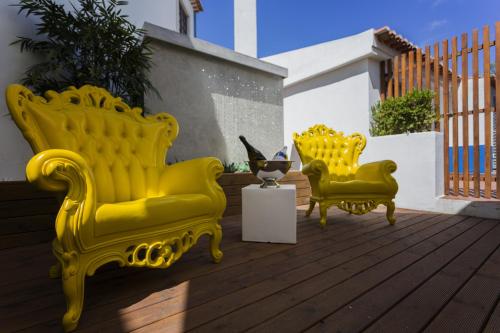 two yellow chairs sitting on a wooden deck at Josefa D`Obidos Hotel in Óbidos