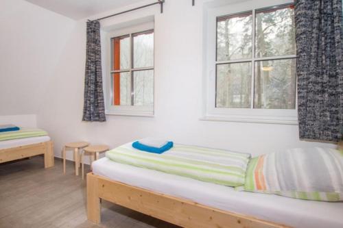 Cette chambre comprend un lit et deux fenêtres. dans l'établissement Ferienhäuser Ilsestein Einzelhaus, 130 qm, 4 Schlafzimmer, à Ilsenburg