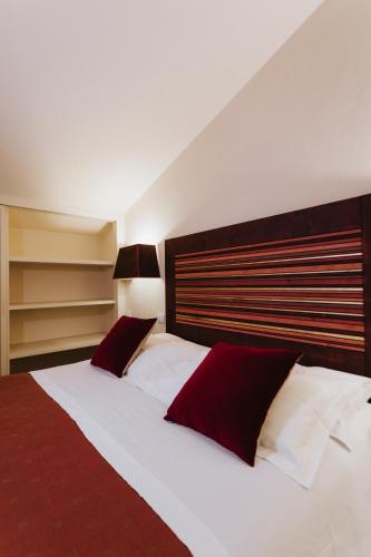 a bedroom with two beds with red and white pillows at Locanda Palazzone in Orvieto