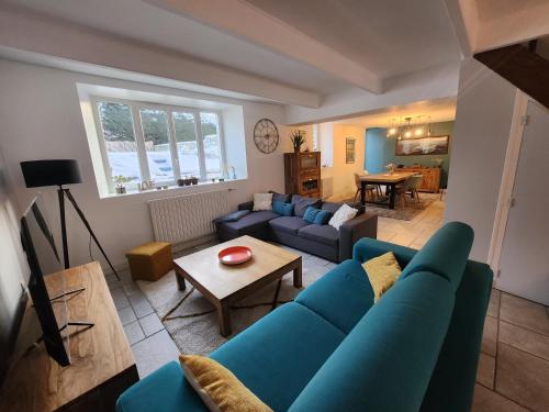 ein Wohnzimmer mit einem blauen Sofa und einem Tisch in der Unterkunft Maison cosy 115m² près de la mer in Hauteville-sur-Mer