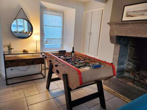 a foosball table in a living room with a fireplace at Maison cosy 115m² près de la mer in Hauteville-sur-Mer