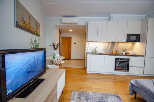 a living room with a large television and a kitchen at Fortune Apartments - City, Contactless in Tartu