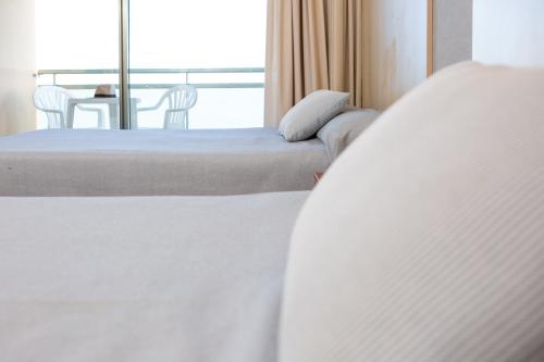 a bedroom with two beds and a view of a balcony at RVHotels Hotel Ametlla Mar in L'Ametlla de Mar