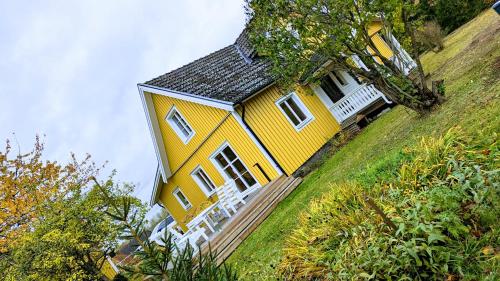 żółty dom na zboczu wzgórza w obiekcie Obstgarten Mörlunda, 5 min zum Badesee, Småland, Sauna w mieście Mörlunda