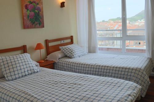 ラレードにあるApartamento Laredoの窓付きのホテルの部屋にベッドが2つある