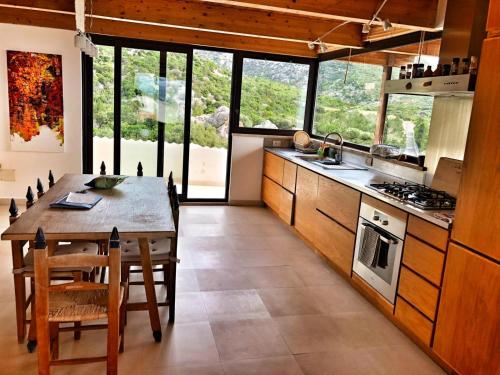 a kitchen with a table and some chairs and some windows at Dreaming the stars - private room in Cala Gonone