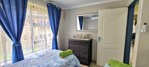 - une chambre avec des rideaux bleus, un lit et une fenêtre dans l'établissement eagles inn, à Richards Bay