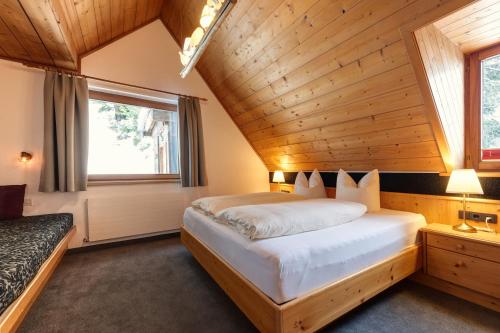 ein Schlafzimmer mit einem großen Bett in einer Holzdecke in der Unterkunft Hotel Pension Kirchplatz in Sankt Anton am Arlberg