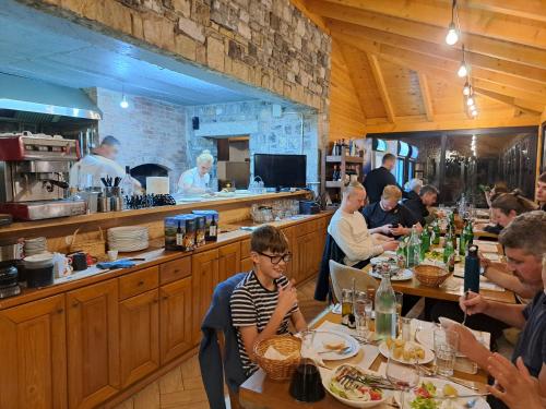 a group of people sitting at tables in a restaurant at Villa Gjeçaj Guesthouse and Restaurant in Theth