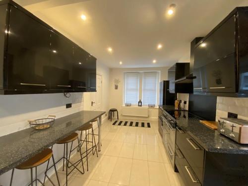 a large kitchen with black counter tops and bar stools at Family Cottage in Llandudno with Parking in Llandudno