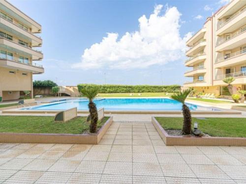 a swimming pool with two palm trees in front of a building at Furadouro Beach Spot in Ovar