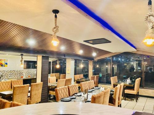 Hotel Aachman Regency with Rooftop Terrace في شيملا: غرفة طعام مع طاولات وكراسي في مطعم