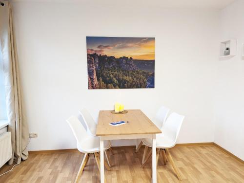 a table and chairs in a room with a painting on the wall at HW1 - Urlaubsmagie - Sauna&Whirlpool zum Entspannen in Sebnitz