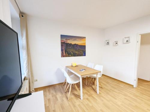 a dining room with a table and chairs and a painting at HW1 - Urlaubsmagie - Sauna&Whirlpool zum Entspannen in Sebnitz