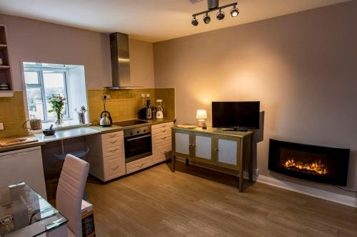 a kitchen with a stove and a fireplace in it at Central Tetbury Apartment 