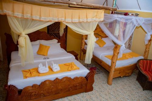 - 2 lits dans une chambre avec un lit à baldaquin dans l'établissement Eco Mara Tented Camp, à Ololaimutiek