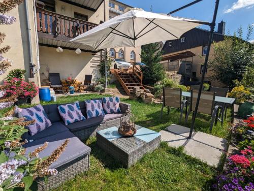 a backyard with a blue couch and an umbrella at HW1 - Urlaubsmagie - Sauna&Whirlpool zum Entspannen in Sebnitz