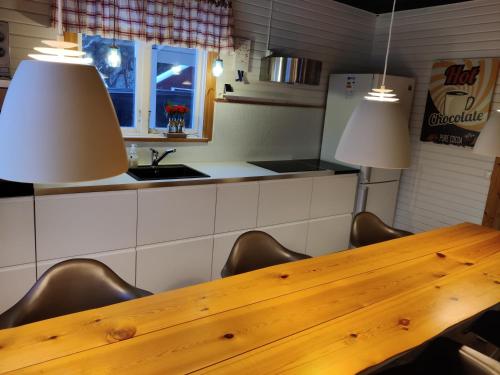 a kitchen with a wooden table with chairs and two lights at Amnerud 5 in Amnerud