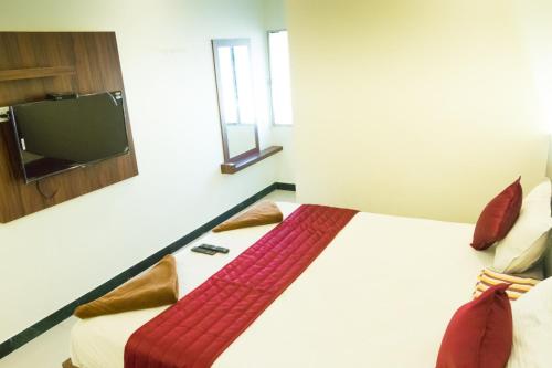 a bedroom with a bed with a tv on the wall at KRR Grand inn in Coimbatore