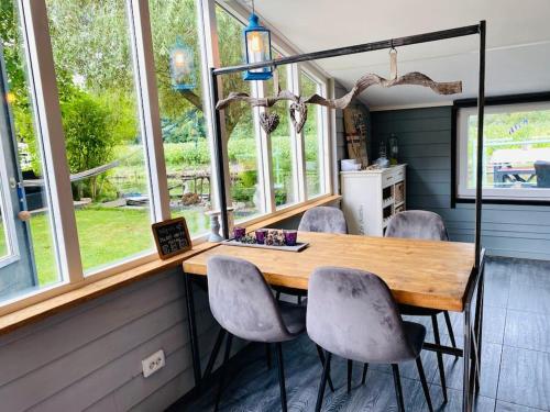 a dining room with a table and chairs and windows at Beautiful house on an island near Amsterdam 