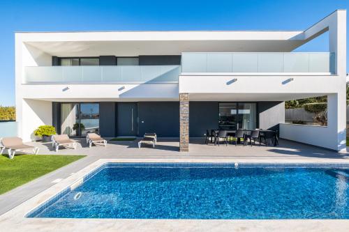 a villa with a swimming pool in front of a house at Villa Aboim - BY BEDZY in Guia