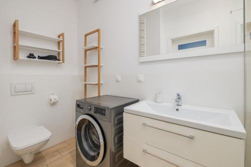 uma casa de banho com uma máquina de lavar roupa e um lavatório em Bulwar Piastowski Chic Apartment em Szczecin