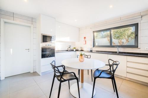 a kitchen with a white table and chairs at Villa Aboim - BY BEDZY in Guia