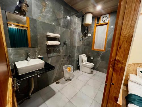a bathroom with a sink and a toilet at Hotel Mid Orchard Kasol l River Side -Pure Veg Hotel in Kasol