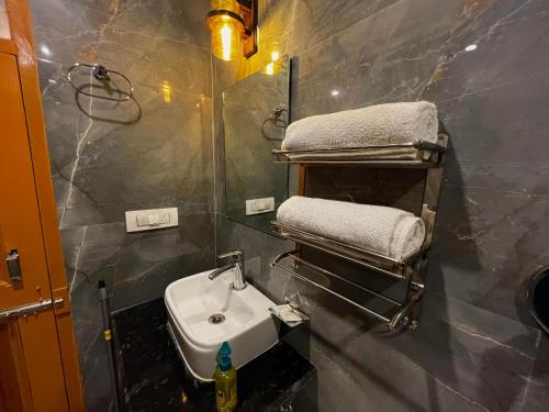 a bathroom with a sink and a towel rack at Hotel Mid Orchard Kasol l River Side in Kasol