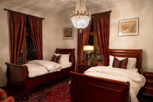 a bedroom with two beds and a chandelier at Villa Eckhoff in Stavanger