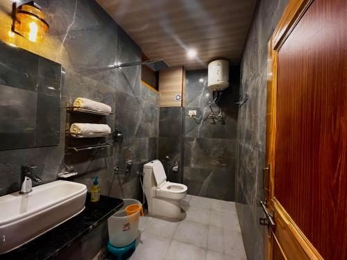 a bathroom with a white toilet and a sink at Hotel Mid Orchard Kasol l River Side -Pure Veg Hotel in Kasol
