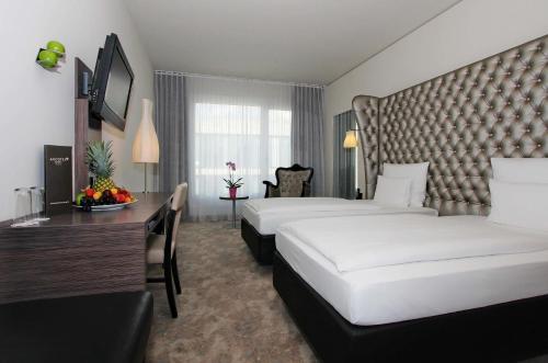 a hotel room with two beds and a desk at ARCOTEL John F Berlin in Berlin
