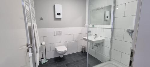 a white bathroom with a toilet and a sink at Hotel Meyer in Bergheim