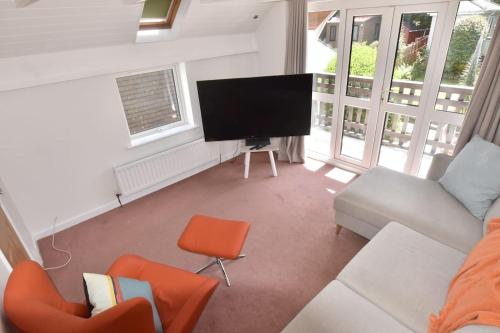 a living room with a tv and a couch and chairs at Family House - Breath Taking Views Over Mounts Bay in Newlyn