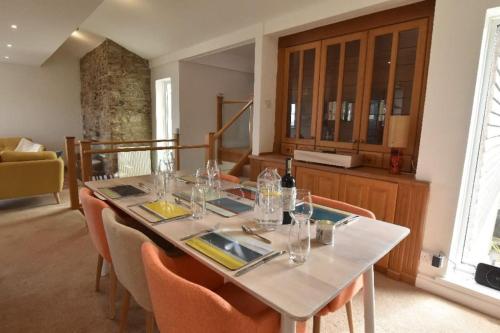 a dining room with a table and chairs with wine glasses at Family House - Breath Taking Views Over Mounts Bay in Newlyn