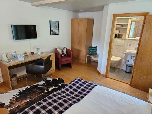 ein Wohnzimmer mit einem Schreibtisch und ein Zimmer mit einem Bad in der Unterkunft Alpina Boutique Hotel Ringgenberg in Ringgenberg