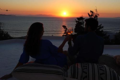 Un uomo e una donna seduti su un cornicione a guardare il tramonto di Hotel Madalena a Mykonos Città