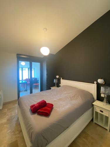 une chambre avec un lit avec deux oreillers rouges dessus dans l'établissement magnifique villa à 50 m de la plage, à La Couarde-sur-Mer