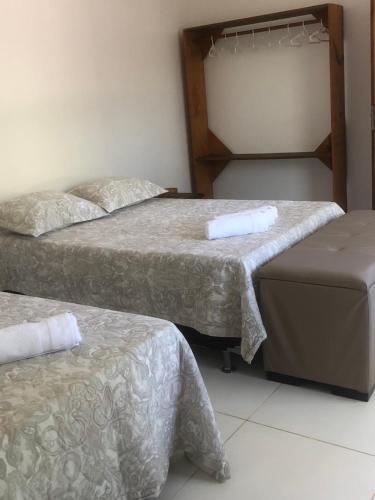 a room with two beds and a ottoman in it at Conchas e Corais Suítes in Marau