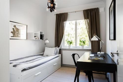 a bedroom with a bed and a desk and a window at WOW Apartments Johanneberg in Gothenburg