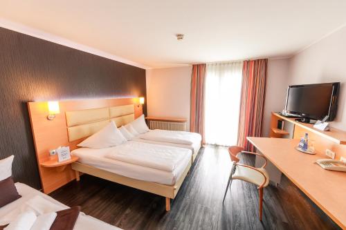 ein Hotelzimmer mit einem Bett und einem TV in der Unterkunft Best Western Plaza Hotel Stuttgart-Ditzingen in Ditzingen