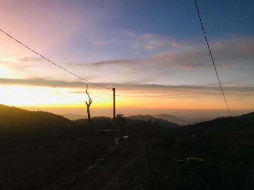 a person standing on top of a hill at sunset at White house in Nuwara Eliya