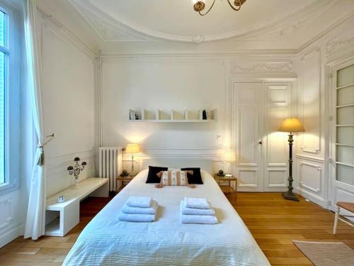 una camera bianca con un grande letto con tre cuscini di L’Hôtel Particulier des Anges a Reims