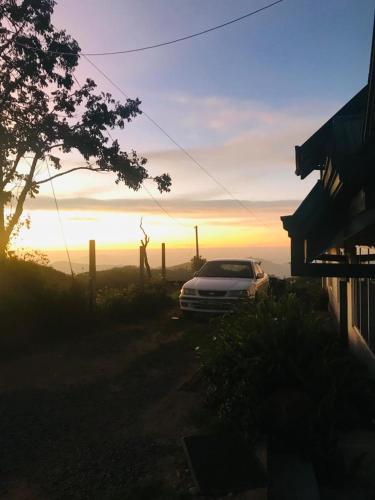 a car parked next to a house with the sunset in the background at White house in Nuwara Eliya