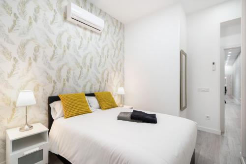 a bedroom with a white bed with yellow pillows at Chueca San Antón Apartment in Madrid