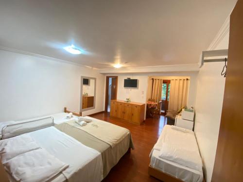 a bedroom with two beds and a television in it at Pousada Habitue in Gramado