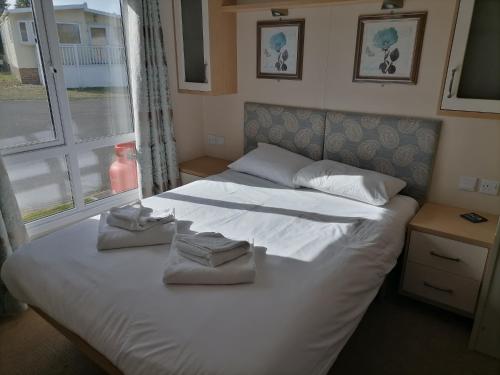 羅切斯特的住宿－Kent Coast Holiday Park，卧室配有带毛巾的大型白色床