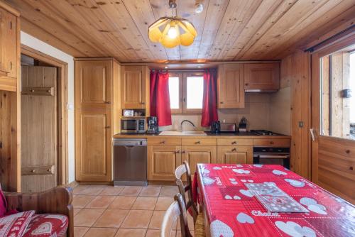 une cuisine avec des placards en bois et une table avec un tissu de table rouge dans l'établissement Appartement les 4 monts, à Megève