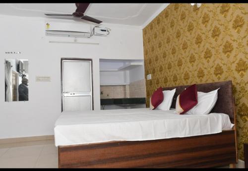 a bedroom with a bed with white sheets and red pillows at Ram Madaiya Home stay in Faizābād